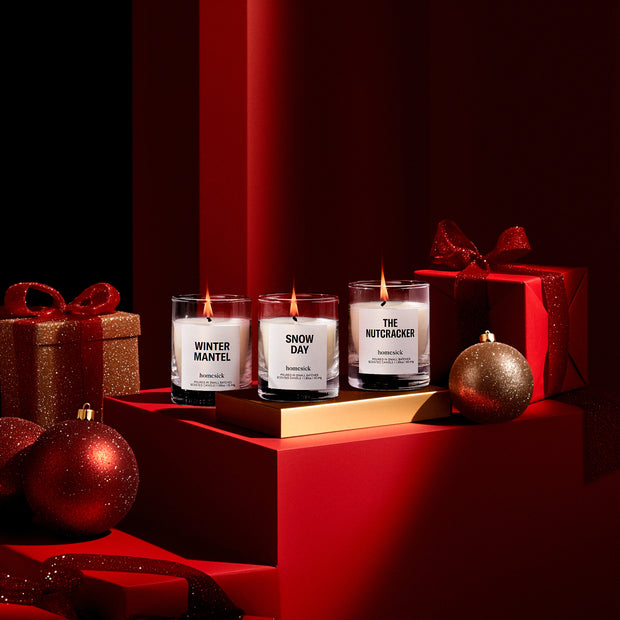 All three lit Winter Wonderland Mini Candles surrounded by presents and Christmas tree ornaments.