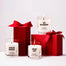 All three lit Winter Wonderland Mini Candles in front of and on top of presents on a white background.