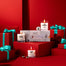 All three lit Winter Wonderland Mini Candles next to their boxed packaging surrounded by presents.