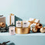 All three lit Winter Wonderland Mini Candles surrounded by presents and Christmas tree ornaments.