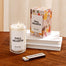 A Fall Hearth Candle and its packaging displayed on a wooden table.