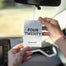 A hand hanging up the Four Twenty Car Freshener in their car.