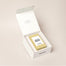 A white candle box that displays how a candle fits perfectly inside. The top lid packaging reads, "where the heart is" and inside is the Let's Toast candle.