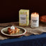 A stylized shot of the Grandma's Kitchen candle next to it's packaging. There is a nice slice of apple pie in the shot.