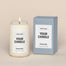 A generic Homesick candle that is lit. The candle label and its packaging display where a customized logo can be added.