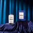 A product shot of the Ravenclaw candle shot on a silky fabric with a blue fabric background.