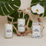A group shot of the celebratory candles available at Homesick. Left to right there is the Let's Toast Candle, Just Married candle and the packaging for Just Married. Behind the products are palm leaves and a wooden branch.