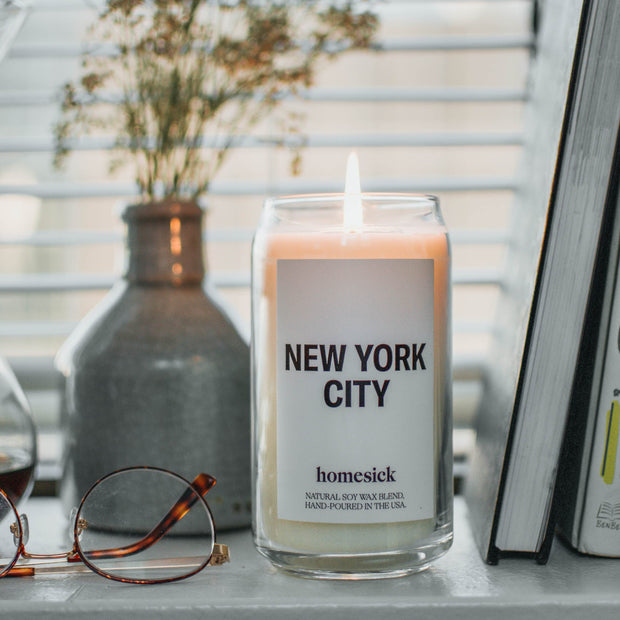 Lit New York City candles sitting on a cozy window sill.