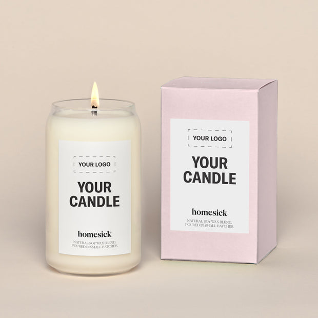 A generic Homesick candle that is lit. The candle label and its packaging display where a customized logo can be added.