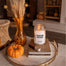 A lifestyle image of the Pumpkin Picking candle shot in a cozy fall apartment. The candle is displayed on a couple of books that also have a box of matches next to them.