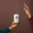 A hand holding the Tennessee candle that another hand just pinched out in front of a light brown surface.
