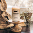 A Tennessee Homesick candle displayed on top of a circular wooden pedestal.
