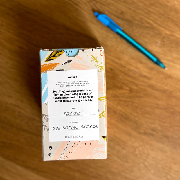 AN overhead shot of the Thanks Candle that shows the back of the packaging and how a custom note can be written.
