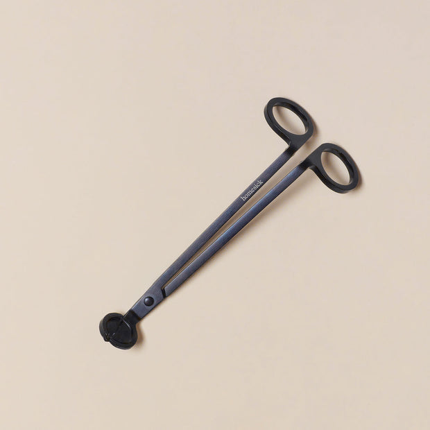 An overhead shot of the Wick Trimmer and its packaging on the right, to be used for optimal candle burnage.
