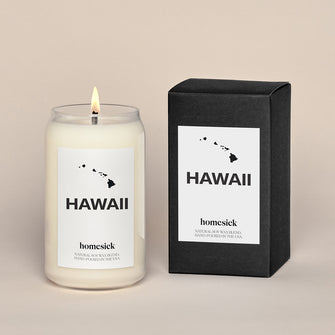 A lit Hawaii candle next the black box that it comes.